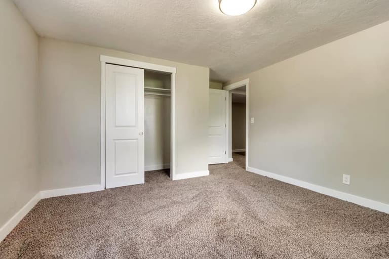 Basement bedroom with sliding-door closet, carpet, and warm neutral walls — Utah basement bedroom by CasaMás Construction