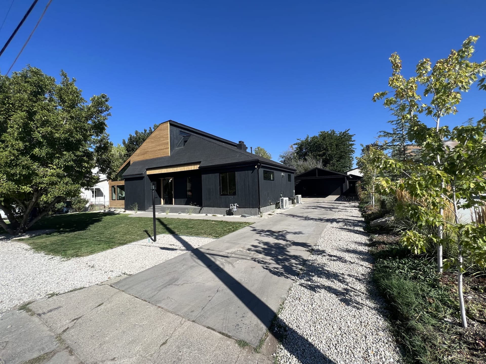 Modern dark vertical-cladding home with wood-clad gable end — finished home addition in Utah by CasaMás Construction