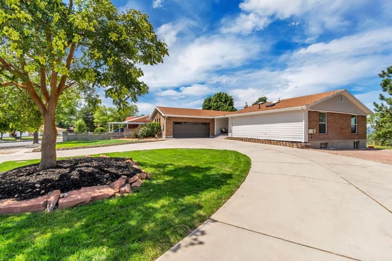 Suburban Utah home with brick and white siding, double garage, and landscaped front yard — home addition by CasaMás Construction