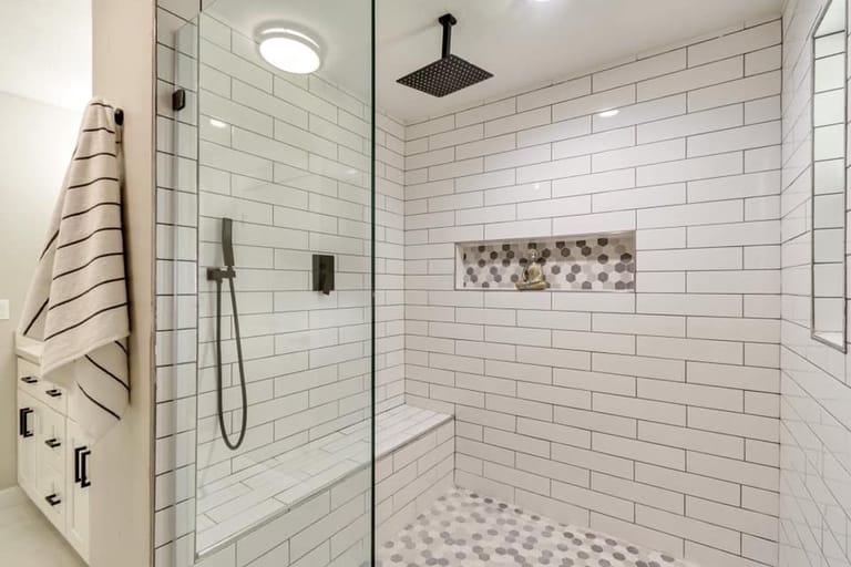 Walk-in shower with white subway tile, hexagon mosaic accent niche and floor, rain shower head, hand wand, and built-in bench — Utah bathroom by CasaMás Construction